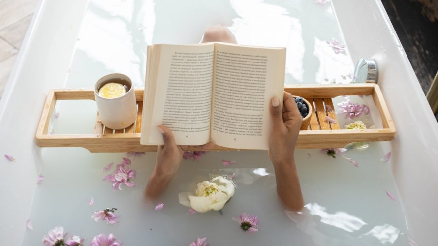 woman reading book while resting in bathtub